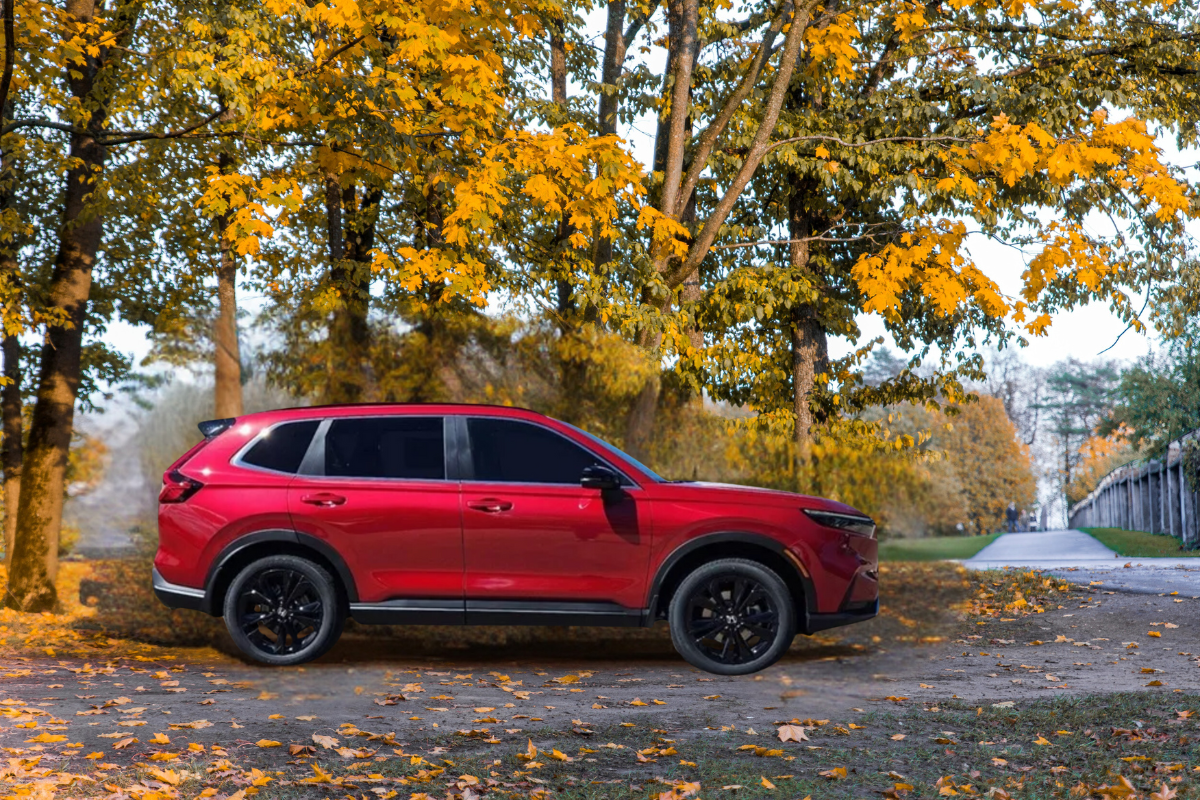 Honda CR V hybrid in red parked under autumn trees