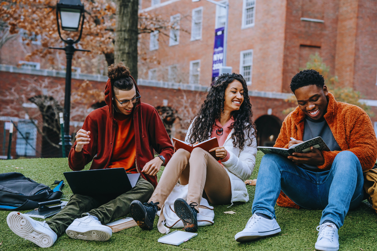 college students sitting on grass and laughing