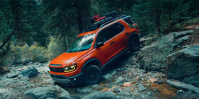 An orange 2026 Honda Passport SUV drives down a rocky embankment in Denver, CO