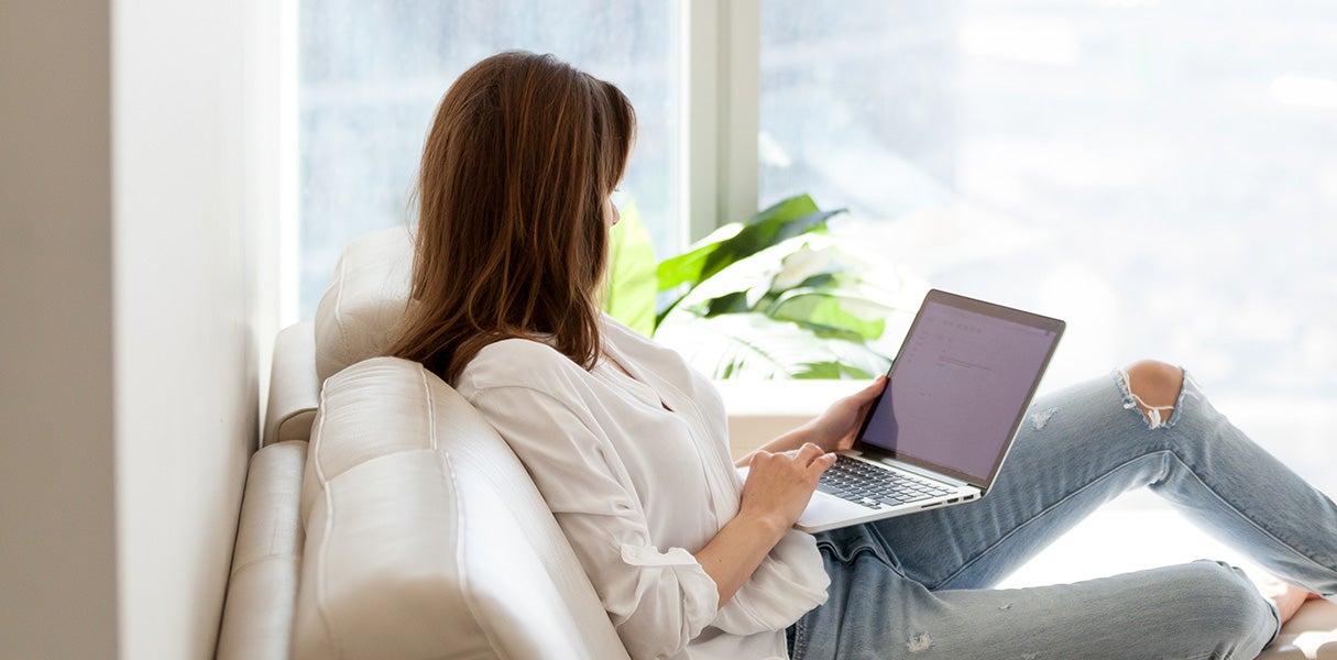 A woman sitting on a couch looking at an iPad